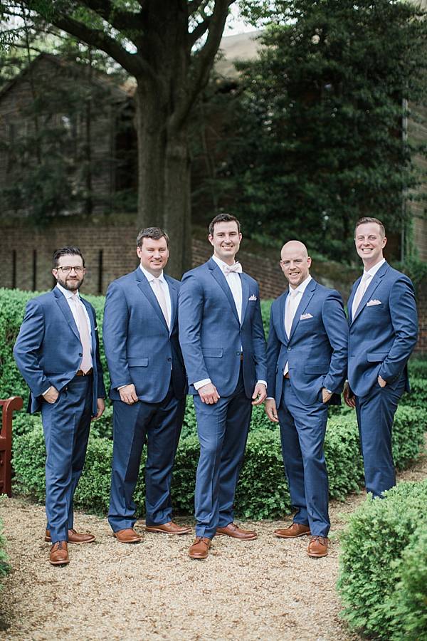 Groomsmen in blue suits with light pink bow ties and brown leather dress shoes.