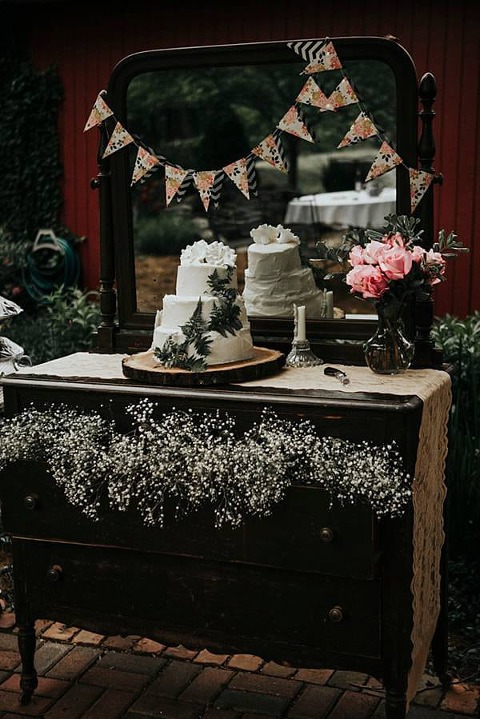 A vintage dresser and mirror were used for the cake table. The table is decorated with paper, roses, lace and babies breath. 